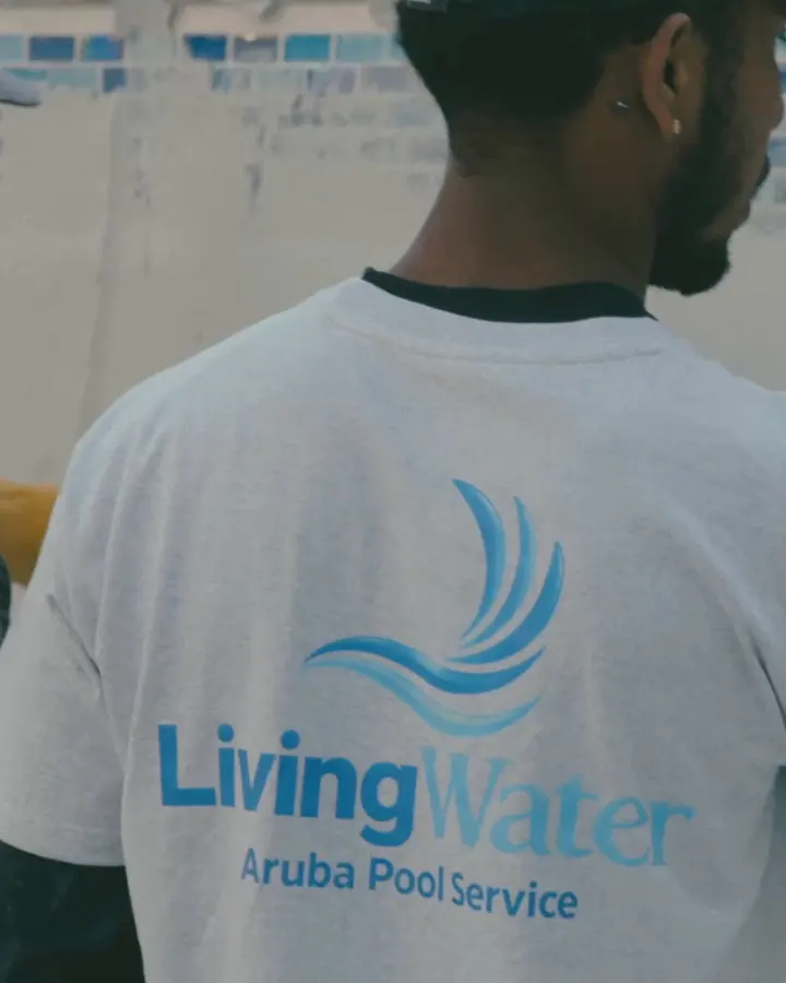 Living Water Aruba technician in a company shirt smoothing the wall of a pool