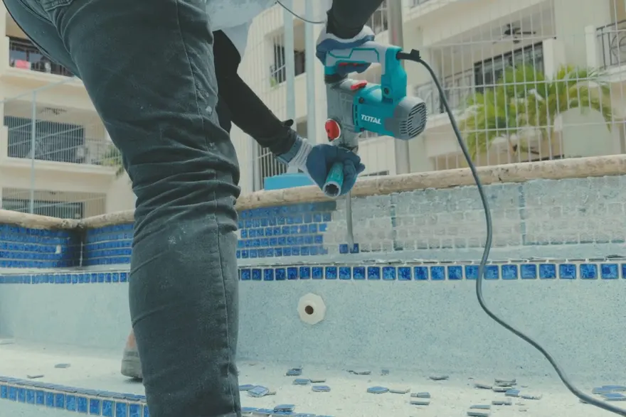 Technician cutting tile at the edge of a pool during a renovation